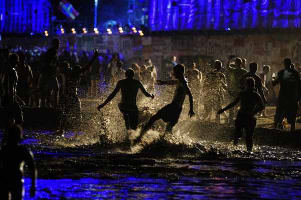 People having fun in the mud pool of the Przystanek Woodstock Music festival in Kostrzyn, Poland.