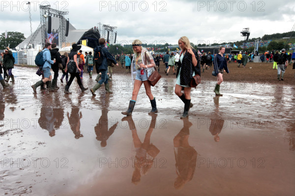 Festival reverlers struggle through the mud at the 2014 Glastonbury Festival.