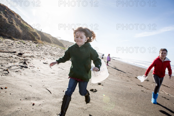 Girls picking up trash on beach cleanup day.