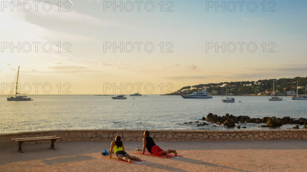 A man and a woman practice yoga early in the morning overlooking Antibes, Cote d'Azur, France