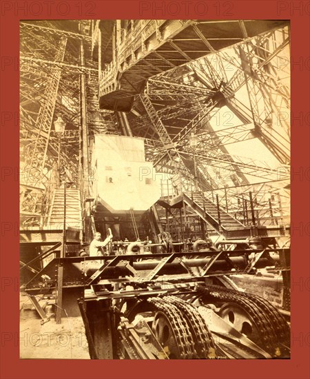 Eiffel Tower machinery with a man beside the wheel that raises elevator, during the Paris Exposition, France, between 1887 and 1889, Napoleon Dufeu