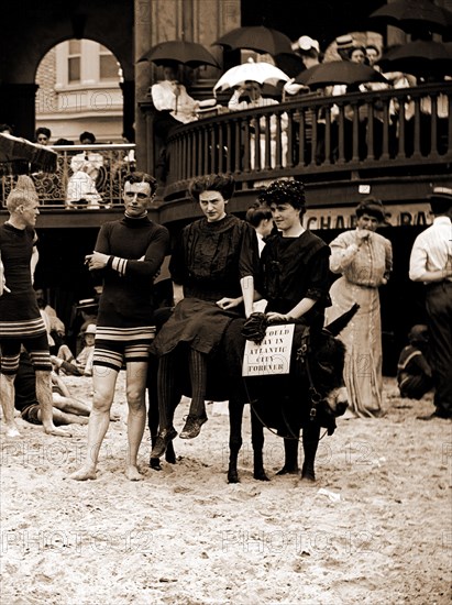 Man and women posed on donkey for photo at crowded beach, Atlantic City, N.J, Beaches, Donkeys, Couples, Tourist trade, United States, New Jersey, Atlantic City, 1900