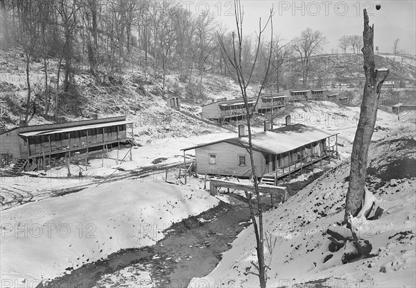 Scott's Run, West Virginia. The Patch - One of the worst camps in Scott's Run. The stream is an auxiliary branch that flows into Scott's Run can be seen towards the right of this picture. These houses were originally built as single bachelor apartments; there are from six to eight separate housekeeping units in the buildings. Many of them are now occupied by families living in one room, March 1937, Lewis Hine, 1874 - 1940, was an American photographer, who used his camera as a tool for social reform. US,USA