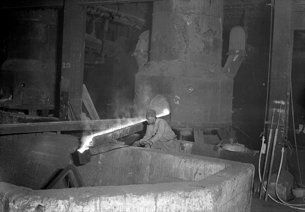 Eddystone, Pennsylvania - Railroad parts. Baldwin Locomotive Works. Moulder takes a small pot of metal from tapped furnace to use on a small job, 1936, Lewis Hine, 1874 - 1940, was an American photographer, who used his camera as a tool for social reform. US,USA