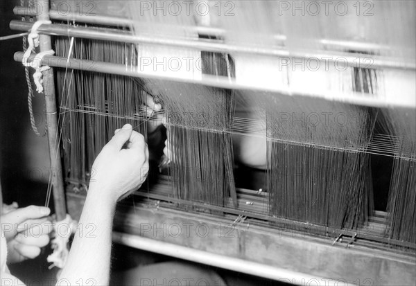Paterson, New Jersey - Textiles. Wishnack Silk Company. Picture of a warp being entered. Shows the enterer and hand-in at work. The warp is slung from what is known as an entering frame, June 1937, Lewis Hine, 1874 - 1940, was an American photographer, who used his camera as a tool for social reform. US,USA