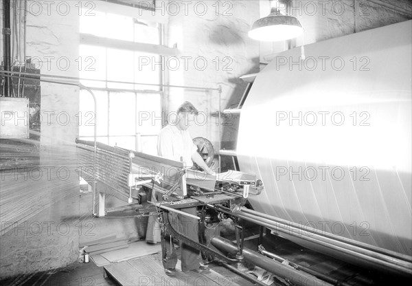 Paterson, New Jersey - Textiles. Jackson Winding and Warping Company. Picture of a Sipp-Eastwood DY type of High Speed Warper. This machine is similar to the one above except that the warp is wound on to the old type of creel. After the warp is made up it is beamed. On this type of machine it takes from 2-1/4 to 2-1/2 hours to make the usual type of warp. This estimate of time may vary slightly one way or the other, depending upon the number of sections, length of the warp, etc, June 1937, Lewis Hine, 1874 - 1940, was an American photographer, who used his camera as a tool for social reform. US,USA