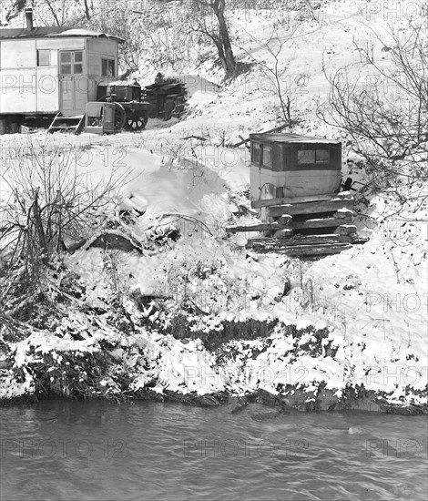 Scott's Run, West Virginia. Outdoor privy - Scene taken from the main highway. The stream is Scott's Run. This privy is typical of many improvised outdoor toilets on Scott's Run. It is made from an old automobile; the house at left is also improvised by the family who occupy it. A stream of water flows past the privy into Scott's Run, March 1937, Lewis Hine, 1874 - 1940, was an American photographer, who used his camera as a tool for social reform. US,USA