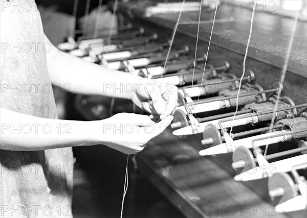 Paterson, New Jersey - Textiles. Quiller tying the broken ends of thread being wound on to quills, March 1937, Lewis Hine, 1874 - 1940, was an American photographer, who used his camera as a tool for social reform. US,USA