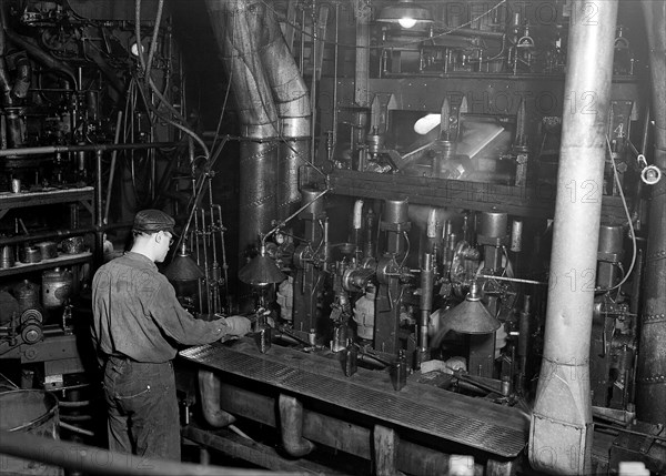 Millville, New Jersey - Glass bottles. Whitall Tatum Co. Second shot of a worker taking a bottle of of an I. S. automatic blowing machine for testing, March 1937, Lewis Hine, 1874 - 1940, was an American photographer, who used his camera as a tool for social reform. US,USA