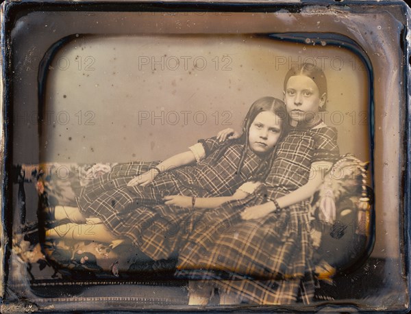 [Portrait of two girls reclining on chaise lounge]