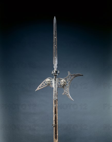 Halberd, c. 1600-1625. France, early 17th century. Steel, pierced; appliqué masks in brass; octagonal wood haft with studs and leather straps; overall: 239 cm (94 1/8 in.); blade: 48 cm (18 7/8 in.).
