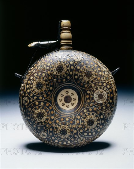 Powder Flask, c. 1620-1650. Germany, 17th century. Walnut inlaid with horn in concentric circles; turned bone funnel with brass spring cap; iron suspension loops; diameter: 12.1 cm (4 3/4 in.); overall: 15.9 cm (6 1/4 in.).
