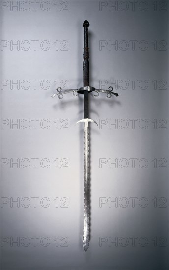 Two-Handed Sword with Flamboyant Blade, 1550-1600. Germany, second half 16th Century. Steel, leather and wood grip with brass rivets; bronze pommel; overall: 168.9 cm (66 1/2 in.); blade: 118.7 cm (46 3/4 in.); quillions: 50.5 cm (19 7/8 in.); grip: 49.2 cm (19 3/8 in.); ricasso: 26.7 cm (10 1/2 in.).