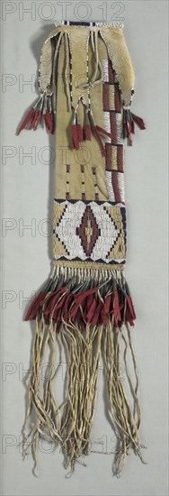 Pipe Bag, c. 1870. America, Native North American, Plains, Tsitsistas (Cheyenne) people, Post-Contact. Native-tanned hide with yellow pigment, glass beads, red trade cloth, tin cones, sinew thread; overall: 71.1 x 12.7 cm (28 x 5 in.)