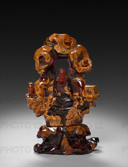 Bodhisattva Guanyin Seated in a Rock Grove, 1675-1700. China, Qing dynasty (1644-1911). Opaque ochre and translucent red-orange amber; overall: 22.9 cm (9 in.).