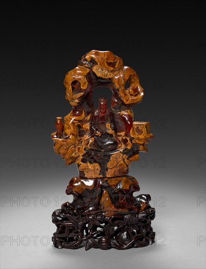 Bodhisattva Guanyin Seated in a Rock Grove, 1675-1700. China, Qing dynasty (1644-1911). Opaque ochre and translucent red-orange amber; overall: 22.9 cm (9 in.).