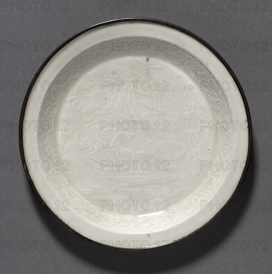Dish with Ducks in Lotus Pond:  Ding Ware, 12th Century. China, Hebei province, Chuyang xian, Jin dynasty (1115-1234). Glazed porcelain with molded decoration and copper band at lip; diameter: 14 cm (5 1/2 in.).