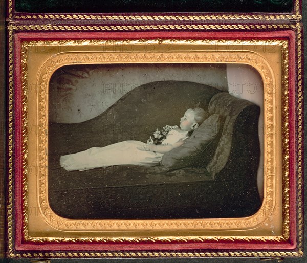 Dead Child On a Sofa, c. 1855. Unidentified Photographer. Daguerreotype, applied color, quarter-plate; image: 6.3 x 8.7 cm (2 1/2 x 3 7/16 in.); case: 11.8 x 9.4 cm (4 5/8 x 3 11/16 in.); mounted: 8.2 x 10.7 cm (3 1/4 x 4 3/16 in.); matted: 50.8 x 61 cm (20 x 24 in.)