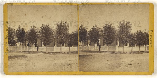 Rocky Mountain Scenery. Man in hat standing in front of a large tree-lined house, with white picket fence; American; about 1870