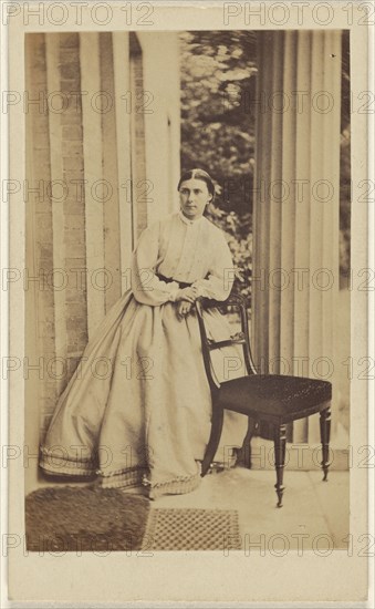 woman standing, leaning on chair back; J.G. & E.G. Short, British, 1865 - 1875; Albumen silver print