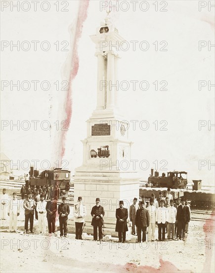 Ottoman dignitaries before railroad monument, locomotives and track in background