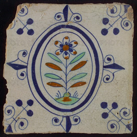 Tile, flower on spot in blue, green, and brown on white, inside an oval with lilies, corner motif, wall tile tile sculpture