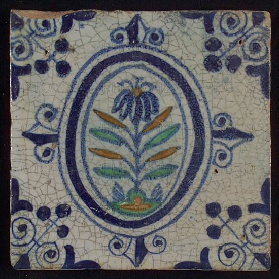 Tile, flower on spot in blue, green, and orange on white, inside an oval with lilies, corner motif, wall tile tile sculpture