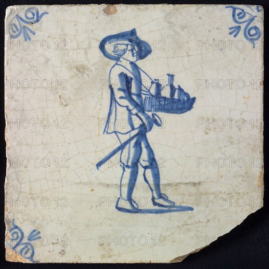 Occupation tile, blue with man with hat and leaf with bottles and walking stick in his hand, corner motif, ox-head, wall tile