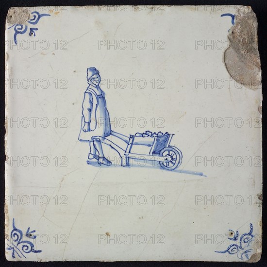 Occupation tile, blue with standing man with wheelbarrow, corner motif oxen head, wall tile tile sculpture ceramic earthenware