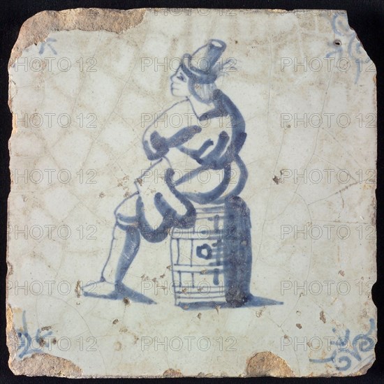 Occupation tile, blue with man sitting on barrel, corner motif ox's head, wall tile tile sculpture ceramic earthenware glaze