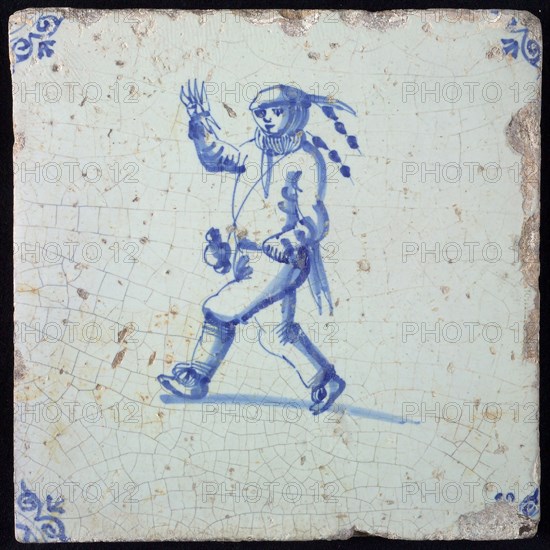 Figure tile, blue with running and waving jester with beer jug on carrying strap, corner motif oxen head, wall tile