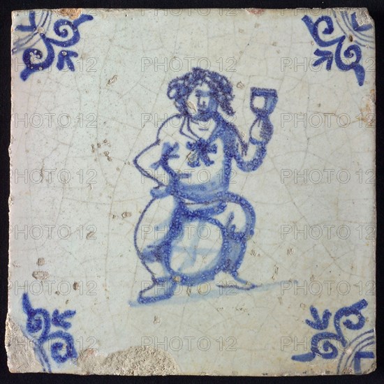 Figure tile, blue with fat man sitting on barrel with raised wineglass, probably Bacchus, corner motif ox's head, wall tile