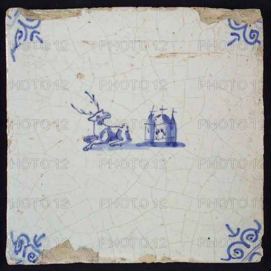 Animal tile, lying deer to the left and right next to it church, in blue on white, corner motif oxen head, wall tile