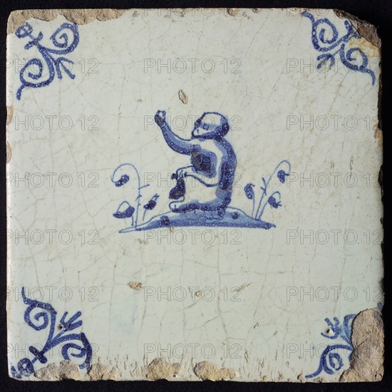 Animal tile, sitting monkey to the left on plot, in blue on white, corner patterned ox head, wall tile tile sculpture ceramic