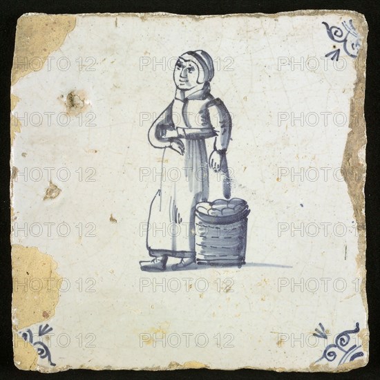 Figure tile, blue with woman with basket of apples next to her, apple-skewer, corner pattern ox-head, wall tile tile sculpture