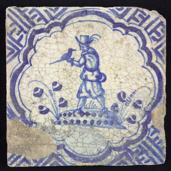 Figure tile, blue with falconer with falcon on the left hand, on ground, in scalloped frame with accolades, corner motif meander