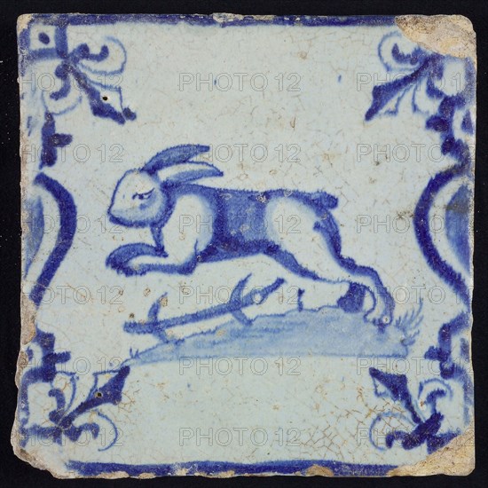 Animal tile, jumping hare to the left on plot between balusters, in blue on white, corner pattern French lily, wall tile