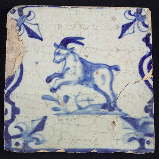 Animal tile, jumping buck to the left on plot between balusters, in blue on white, corner pattern French lily, wall tile