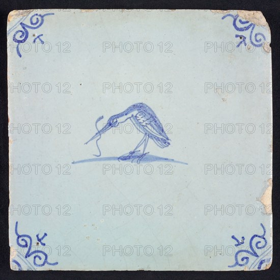 Animal tile, bird with long fish in its beak to the left, blue on white, corner motif ox's head, wall tile tile sculpture