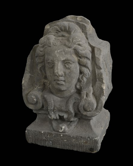 Basement, female head with curly hair on front, cross-shaped band decoration on sides, basement ornament building component