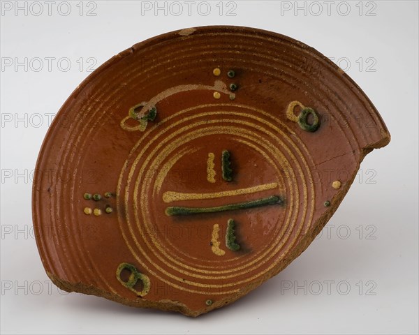 Red earthenware plate with simple silt decor of circles and stripes in yellow and green, plate dish crockery holder soil find