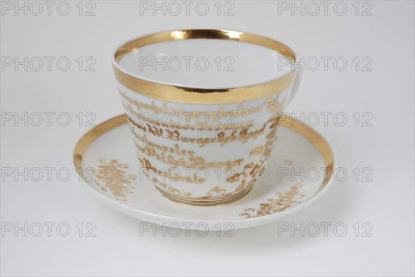 White cup and saucer fifty-year existence Inrigation for Women by Women with gold-colored rim and flower decoration, cup