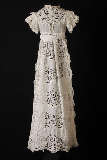 Long wide baby dress in white cotton, front, over sleeves and wide front on the skirt of coarse embroidery with large wheel