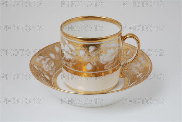 White cup and saucer with gold colored band with acorn and leaf decoration, cup and saucer drinking utensils tableware holder