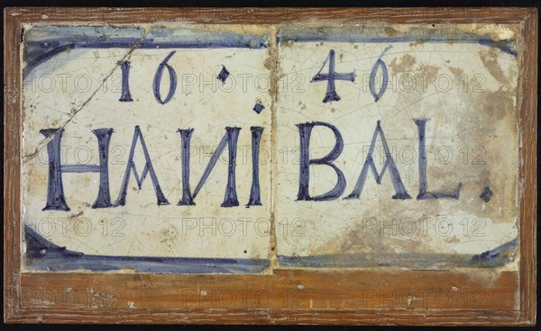 Two tiles next to each other in wooden frame, blue on white, outlined in blue: 1646 and HANIBAL, tile picture material ceramic