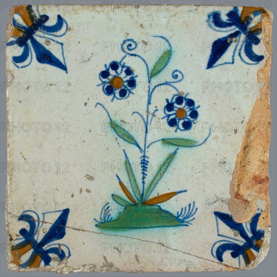 Flower Tile, flower on ground in orange, green and blue on white, corner pattern French lily, corner point orange, wall tile