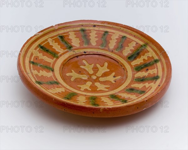 Small earthenware plate with sludge decoration on red background, plate crockery holder soil find ceramic earthenware glaze lead
