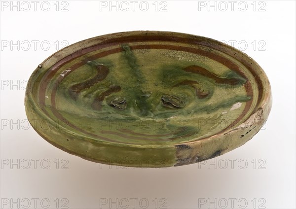 Small earthenware plate on small stand, decorated with brown and green decor on yellow background, plate dish crockery holder