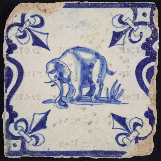 Animal tile, standing elephant to the left on plot between balusters, in blue on white, corner pattern French lily, wall tile