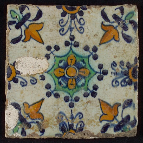 Tile, blue draft, yellow, green and orange on white, central flower within star shape, three-spot around, half rosette, corner